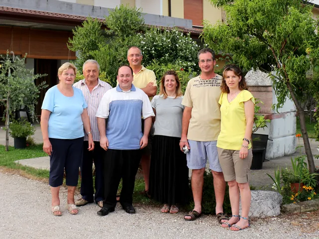 Seven Carlesso relatives standing together in front of a house in Italy.